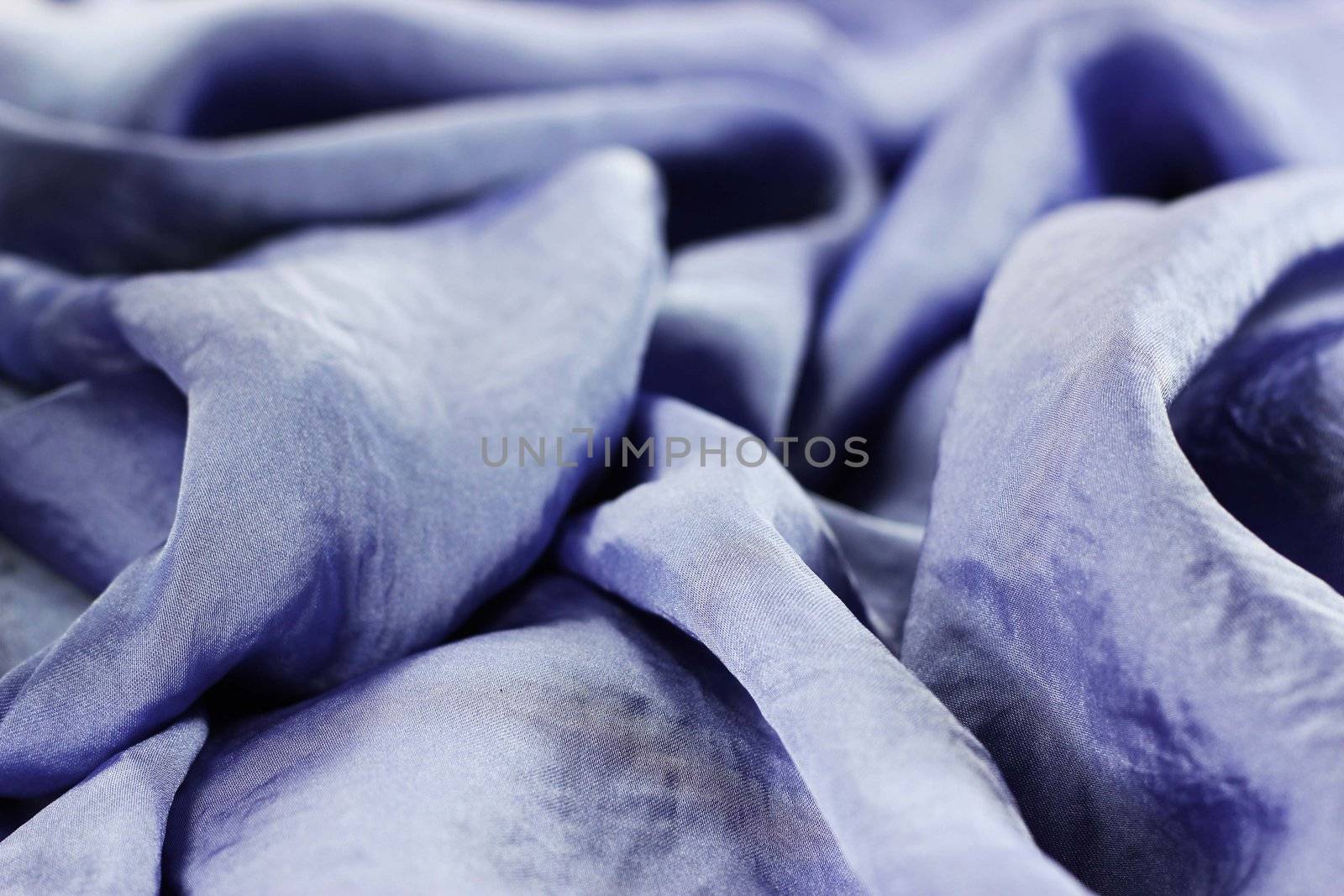 A close up view of the folds and details of shiny violet silk fabric with green beads