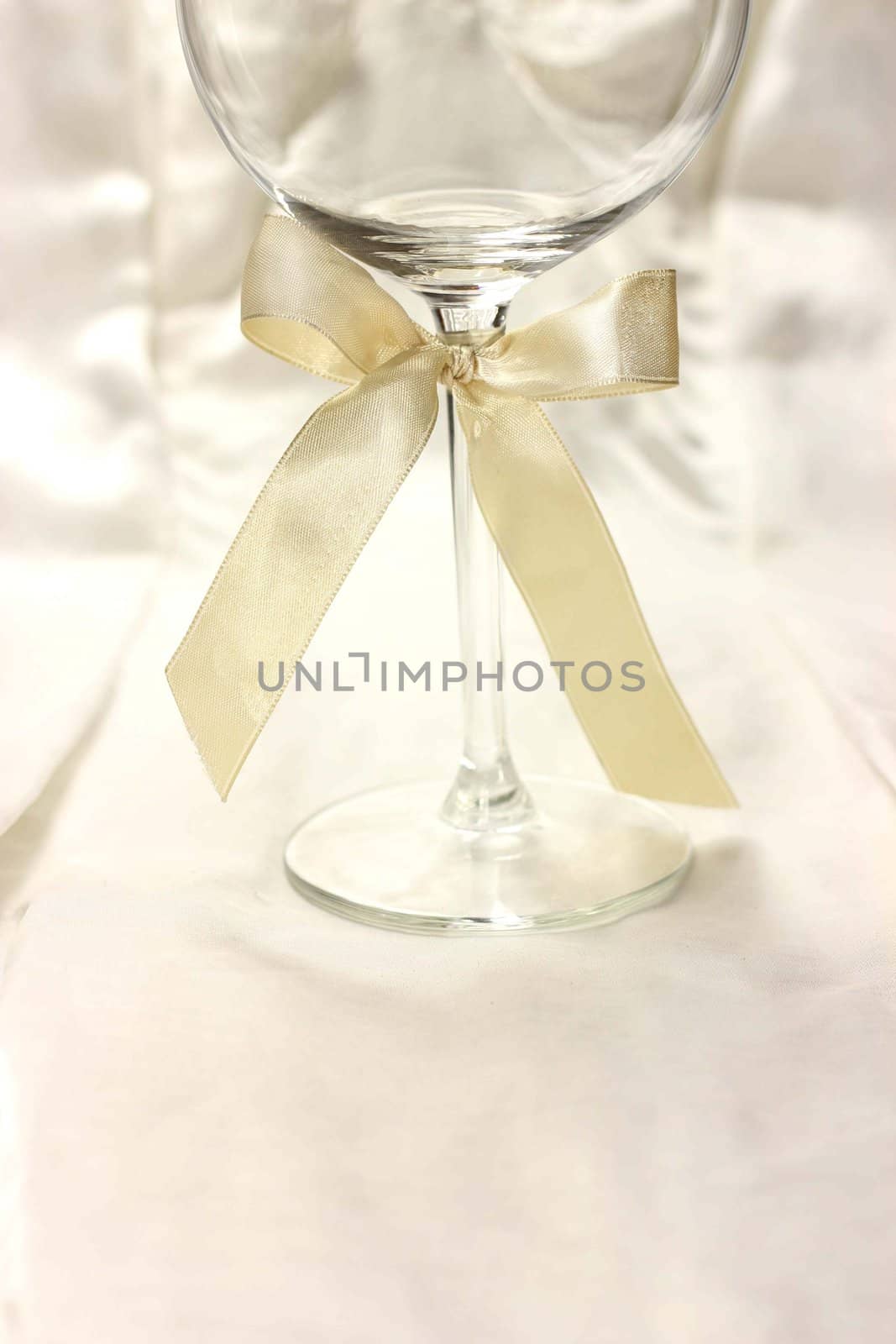 Wineglass with ribbon on silk fair background