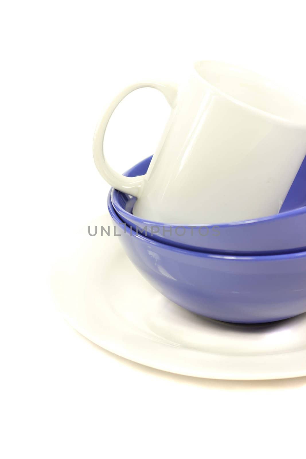 Ceramic white plate, two dark blue bowls and white mug on a white background