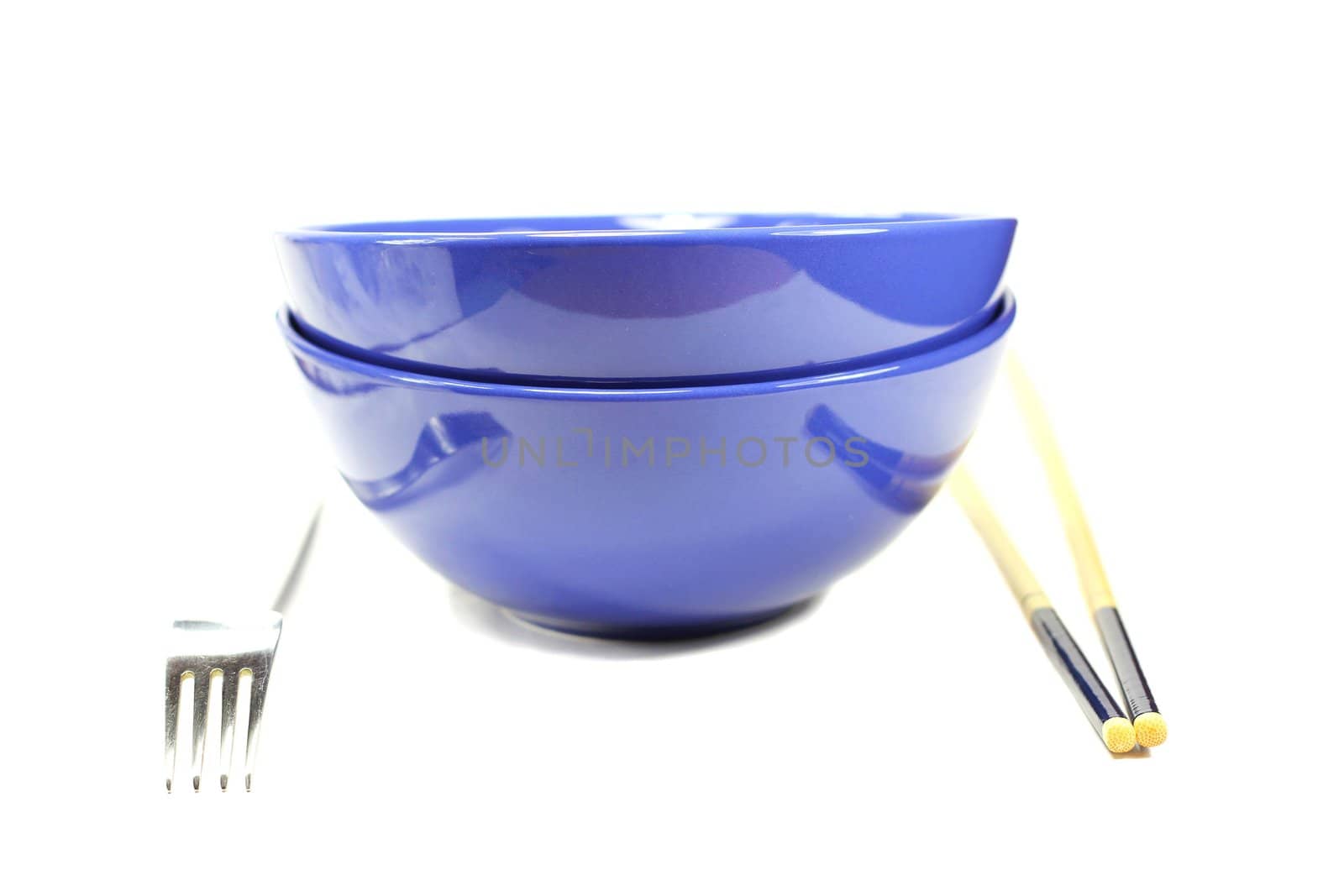Two dark blue bowls, fork and chopsticks on a white background
