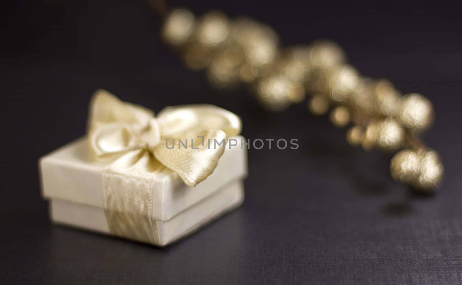 Holiday still life with white gift box and decorative golden glitter branch on a black background