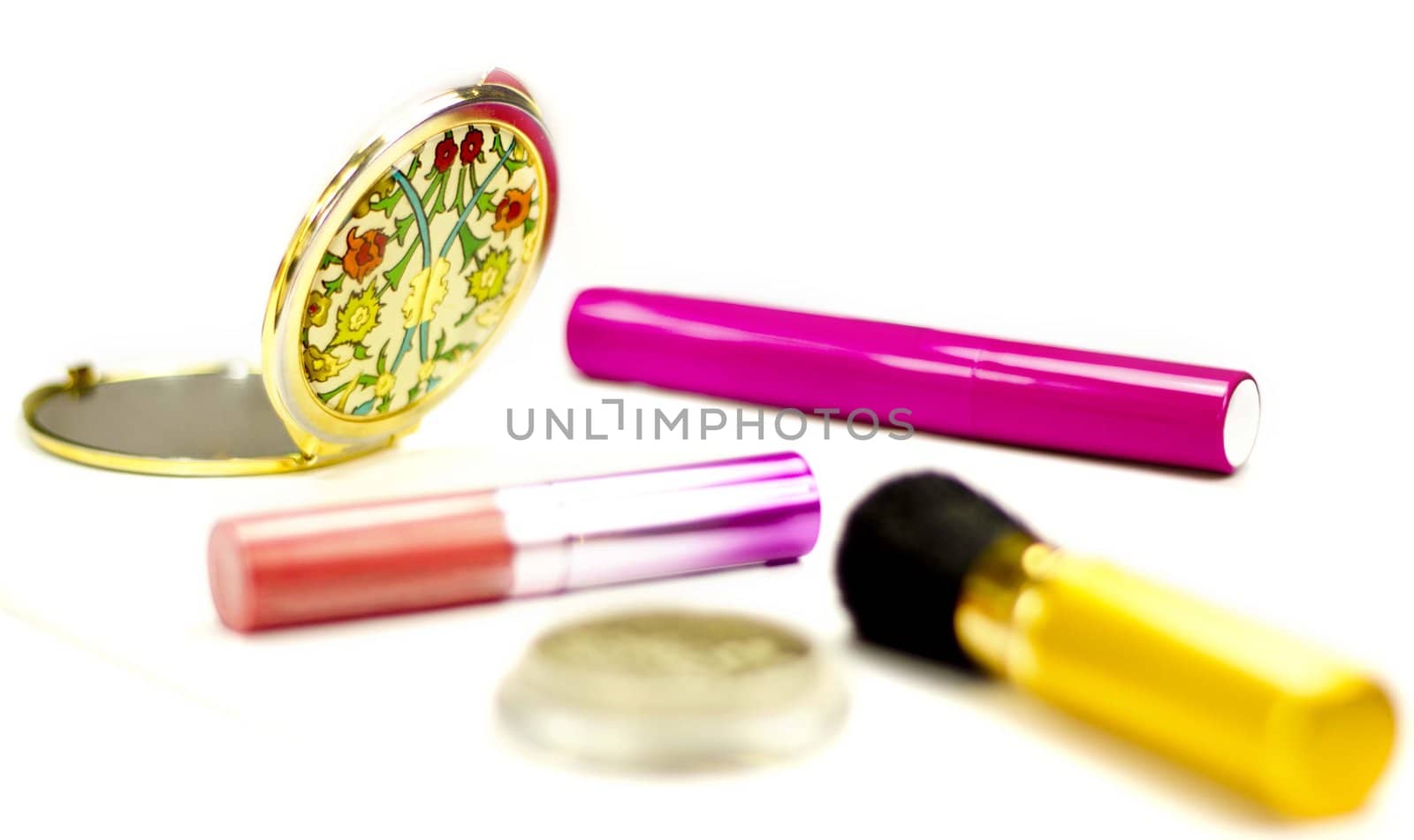 Lip gloss, mirror, mascara, eye-shadows and brush on a white background