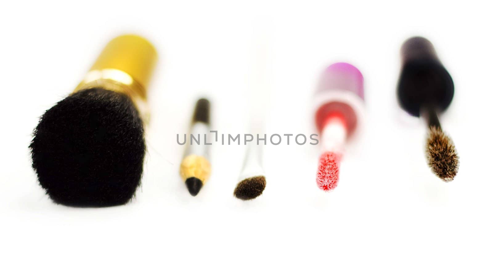 Close-up of eyeliner, applicator for lip gloss and brushes for eye-shadows, brusher and mascara on a white background