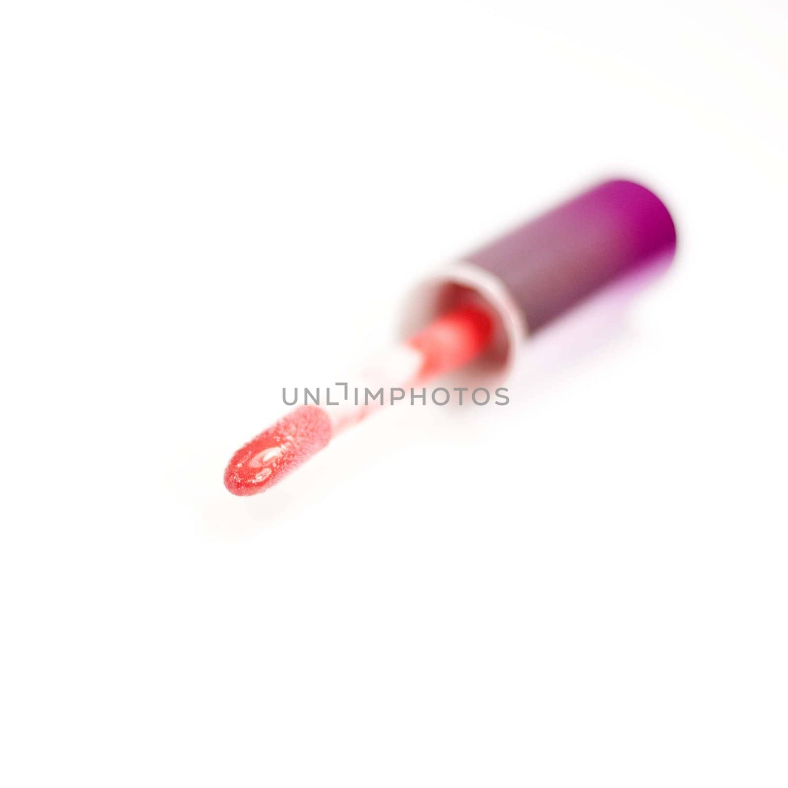 Close-up of lying applicator for pink lip gloss on a white background