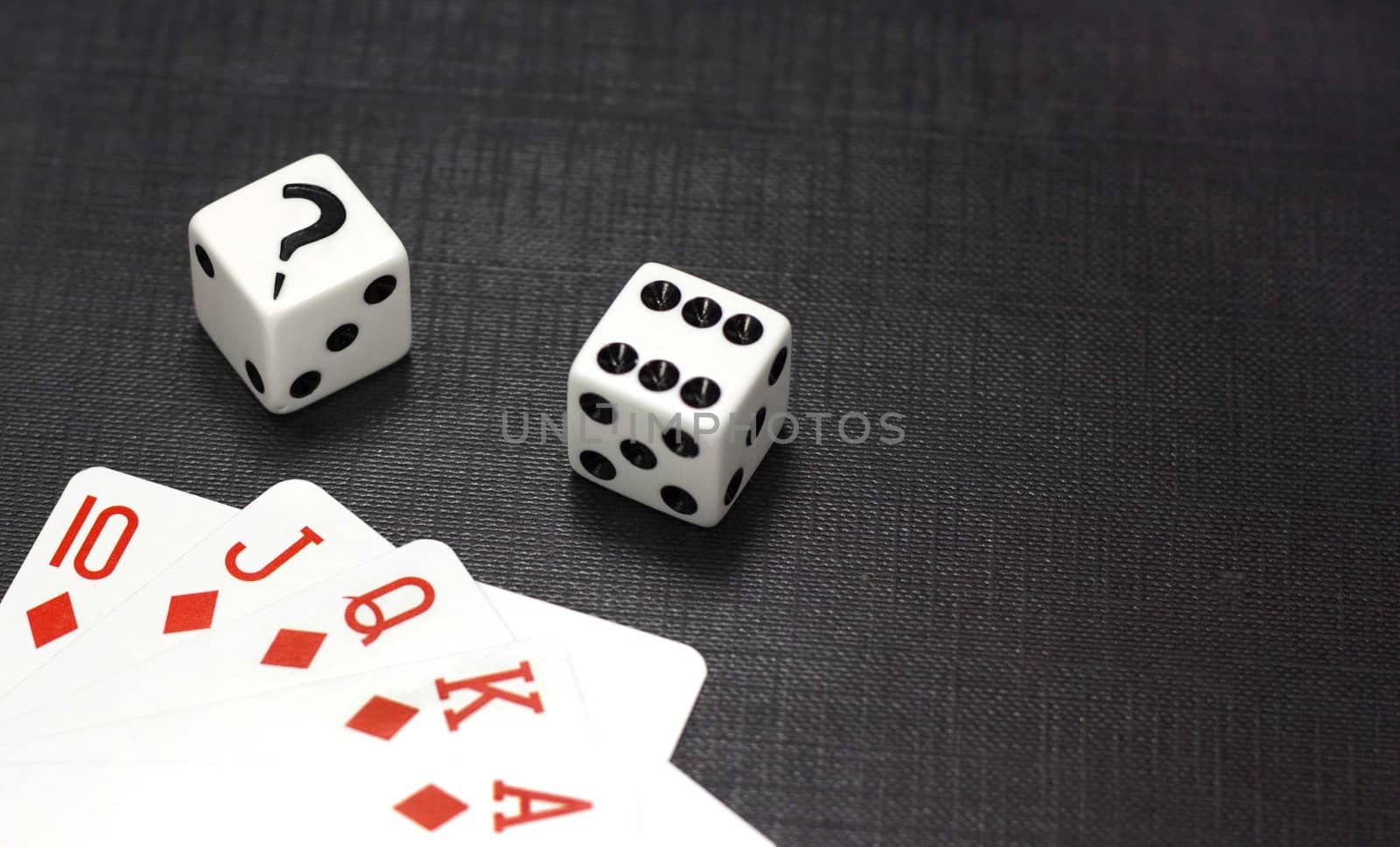 Two white dices and playing cards on a black background