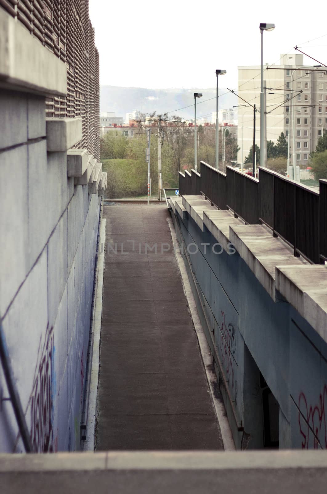 Urban view of asphalt walkway, stone walls and iron fence. Prague