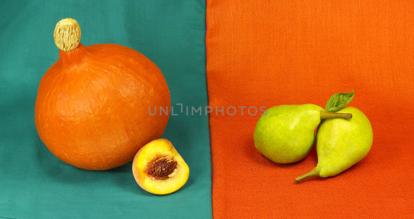 Still life of pumpkin, peach and pears on a colored fabric background