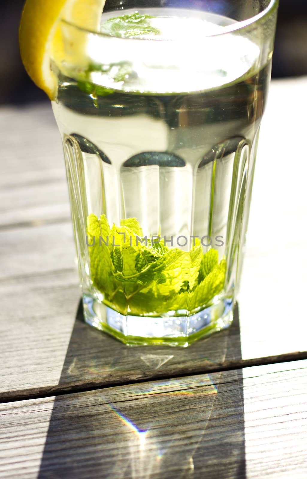 Glass of hot tea with a fresh peppermint and lemon, wooden background