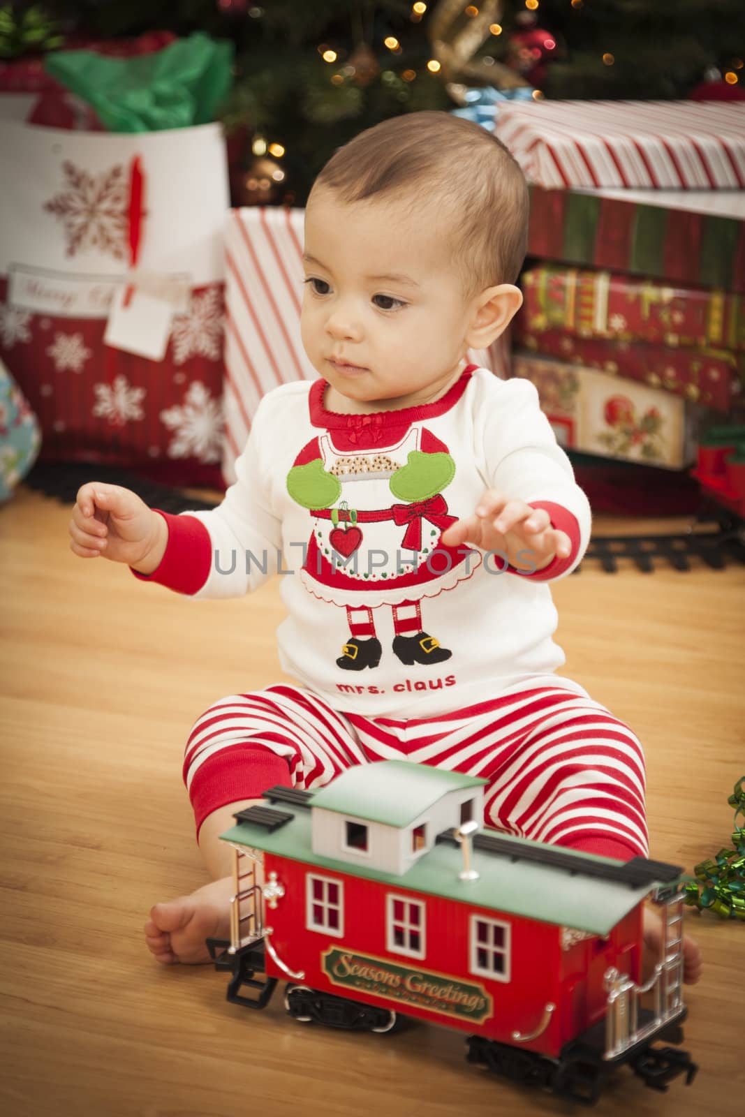 Cute Infant Mixed Race Baby Enjoying Christmas Morning Near The Tree.