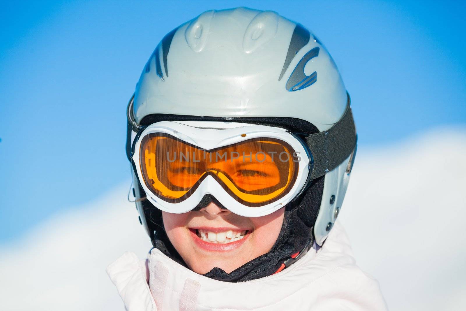 Closeup portrait of young smiling girl in helmet and ski googles at winter outdoor in the Zillertal Arena, Austria