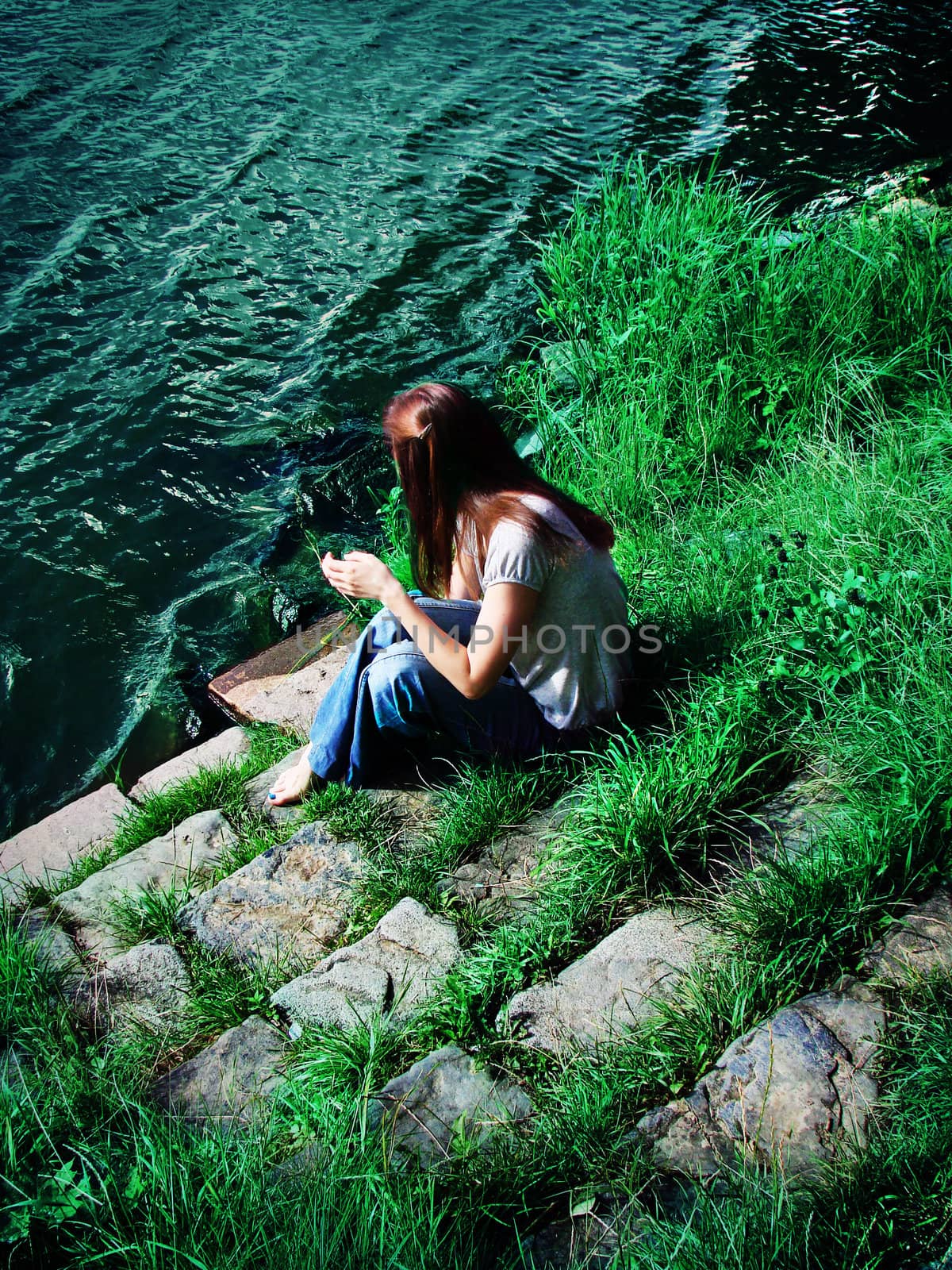 Young woman sitting on the riverbank in a summer day, art photo