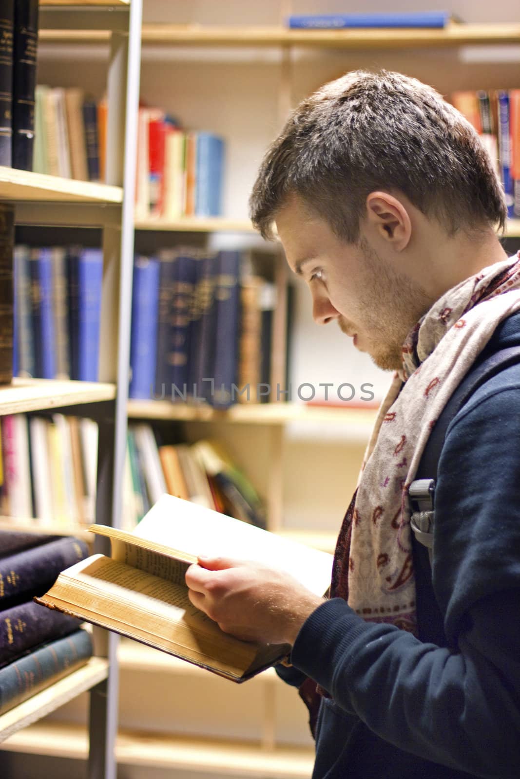 A guy reading a book in a library
