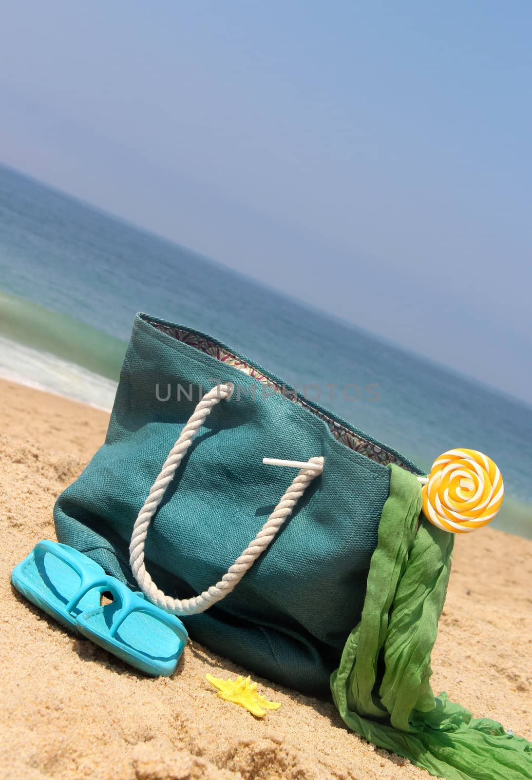 Summer holidays - blue beach bag on the seacoast with lollipop