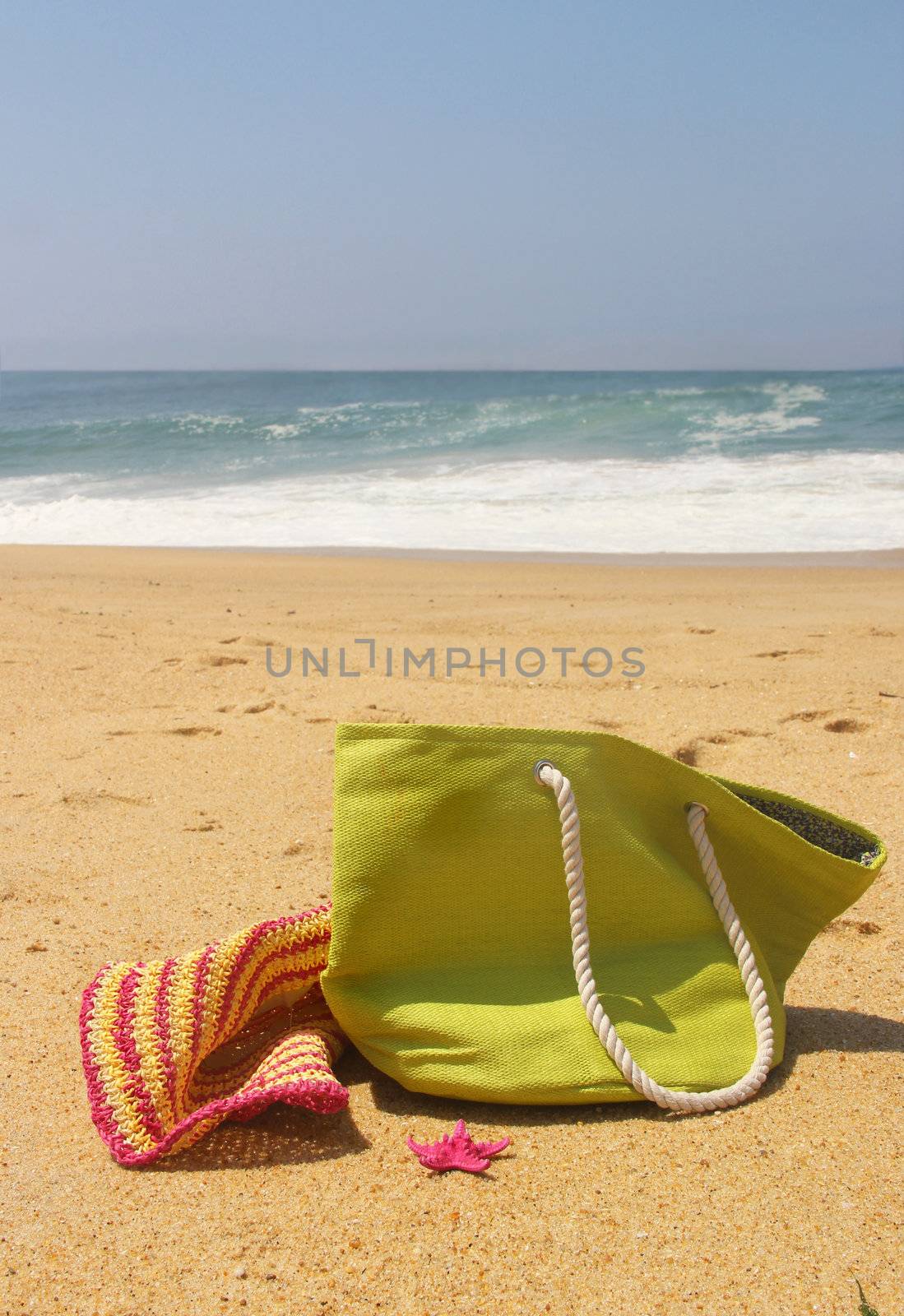 Green beach bag, pink straw hat and starfish