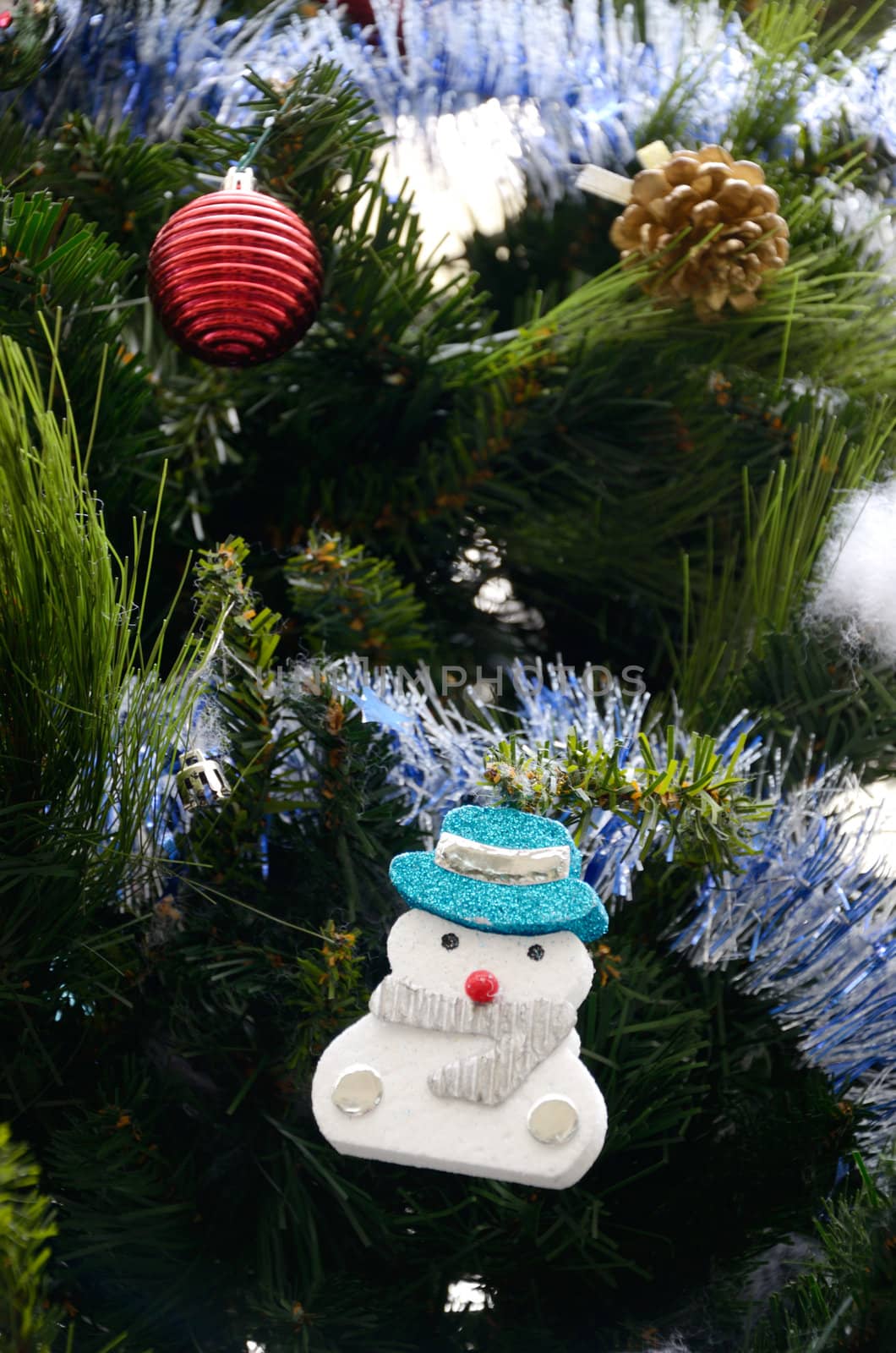 Snow man hanging art on Christmas tree with ornament