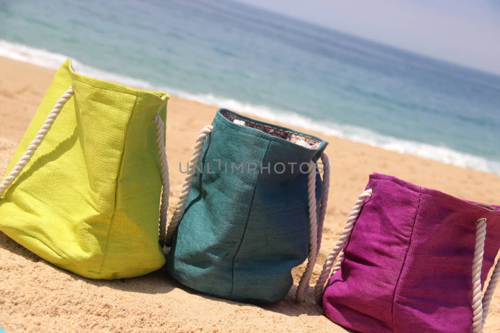 Summer holiday � three vivid bags on the seacoast, green, violet and blue