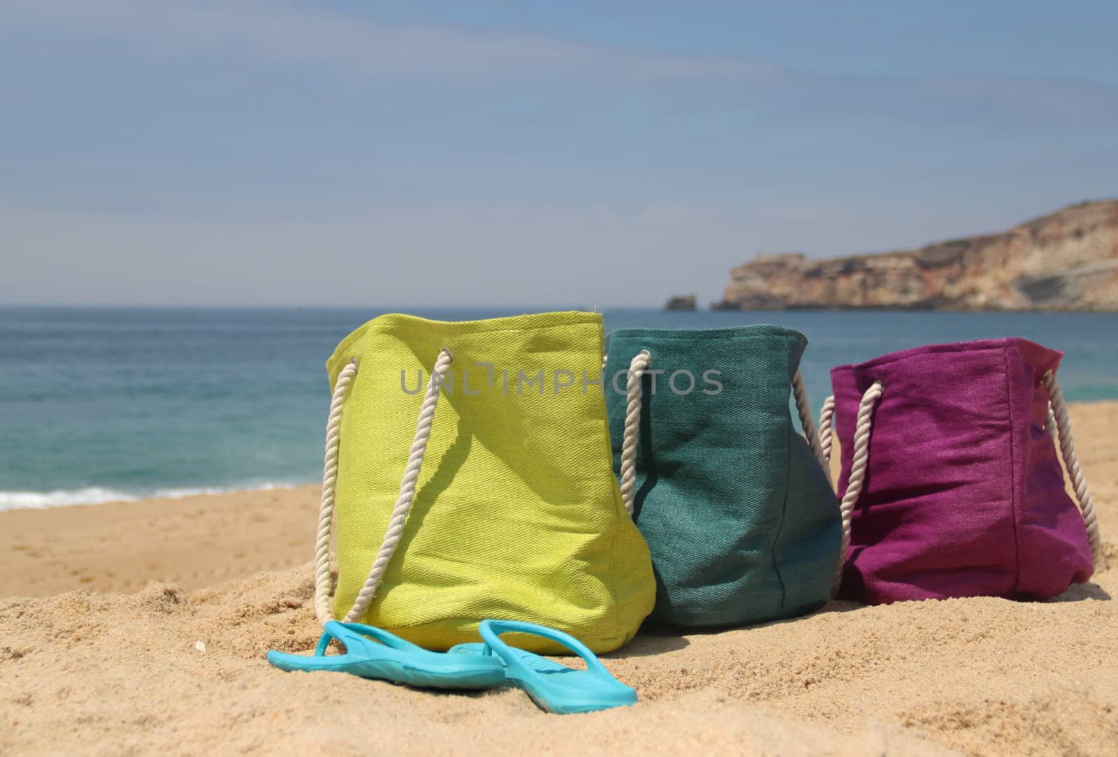 Summer holiday � three vivid bags on the seacoast, green, violet and blue