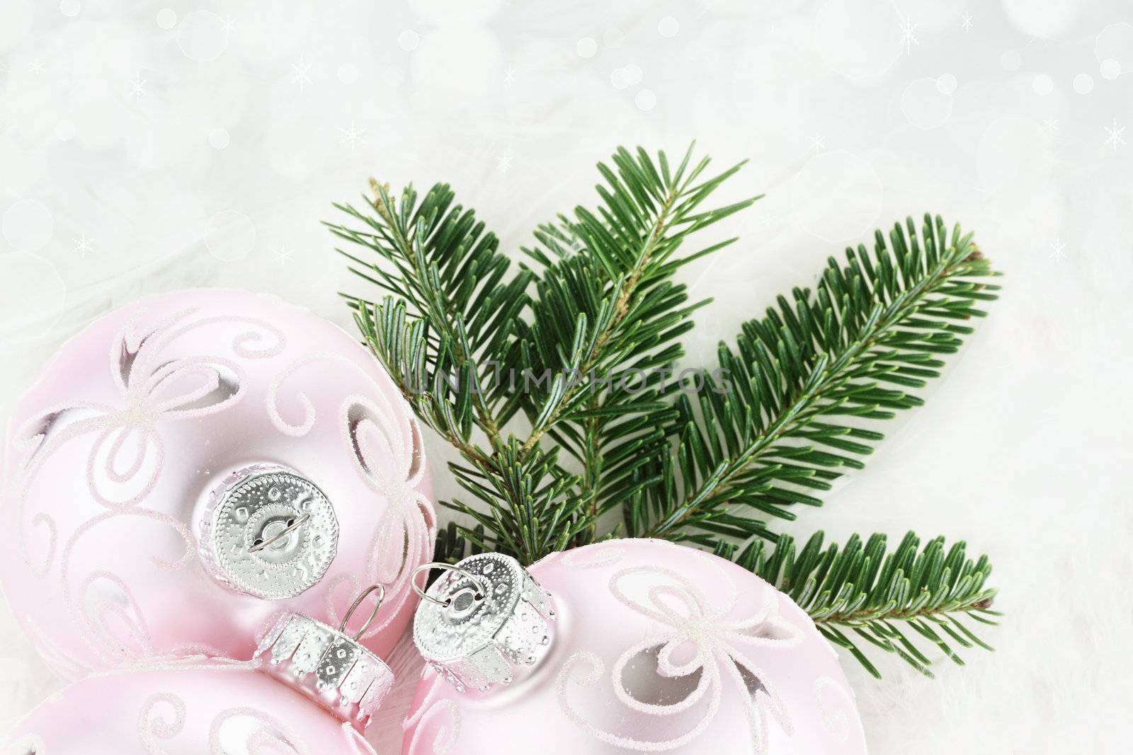 New pink Christmas baubles border with fresh pine over a white sparkly background. 