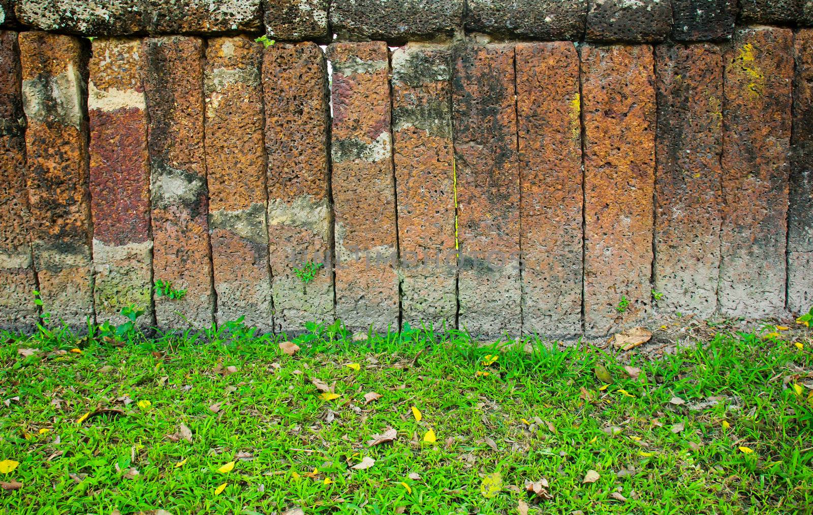 Stone block wall with green grass by nuchylee