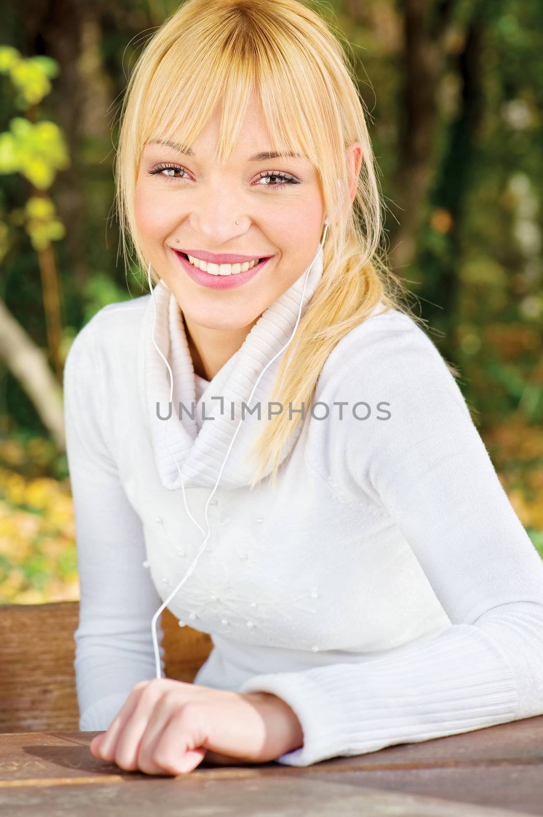 Blond woman with headphones in park