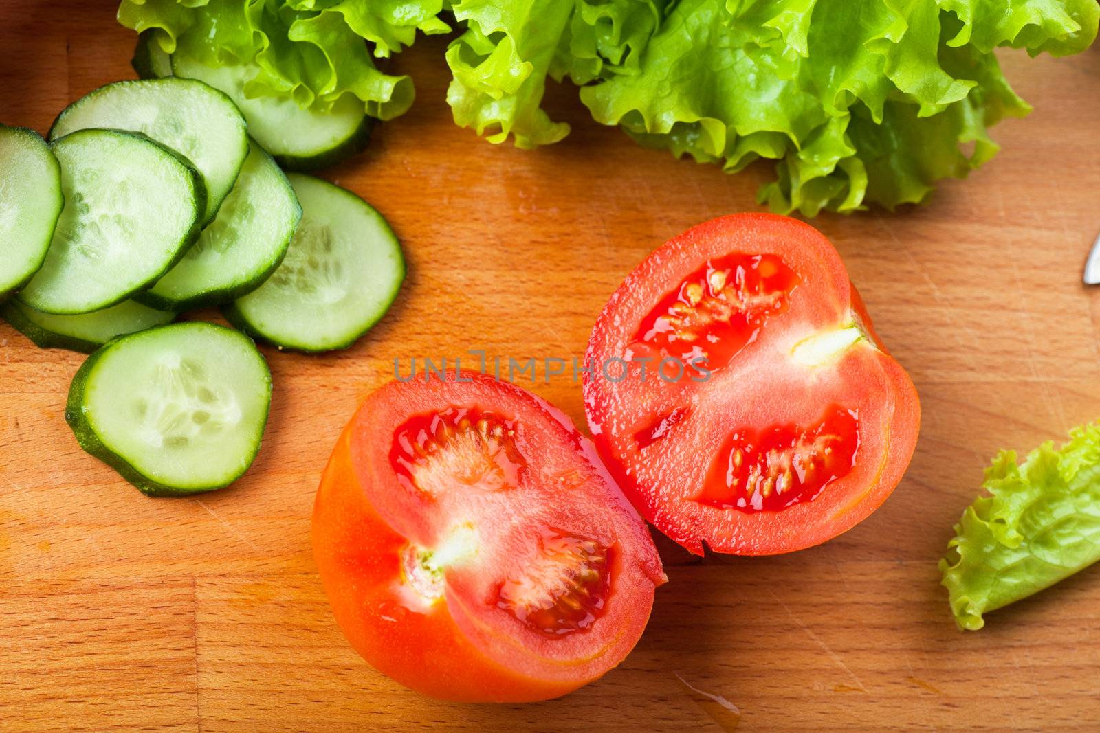 Vegetables (tomato, cucumber, salad) on a wooden table