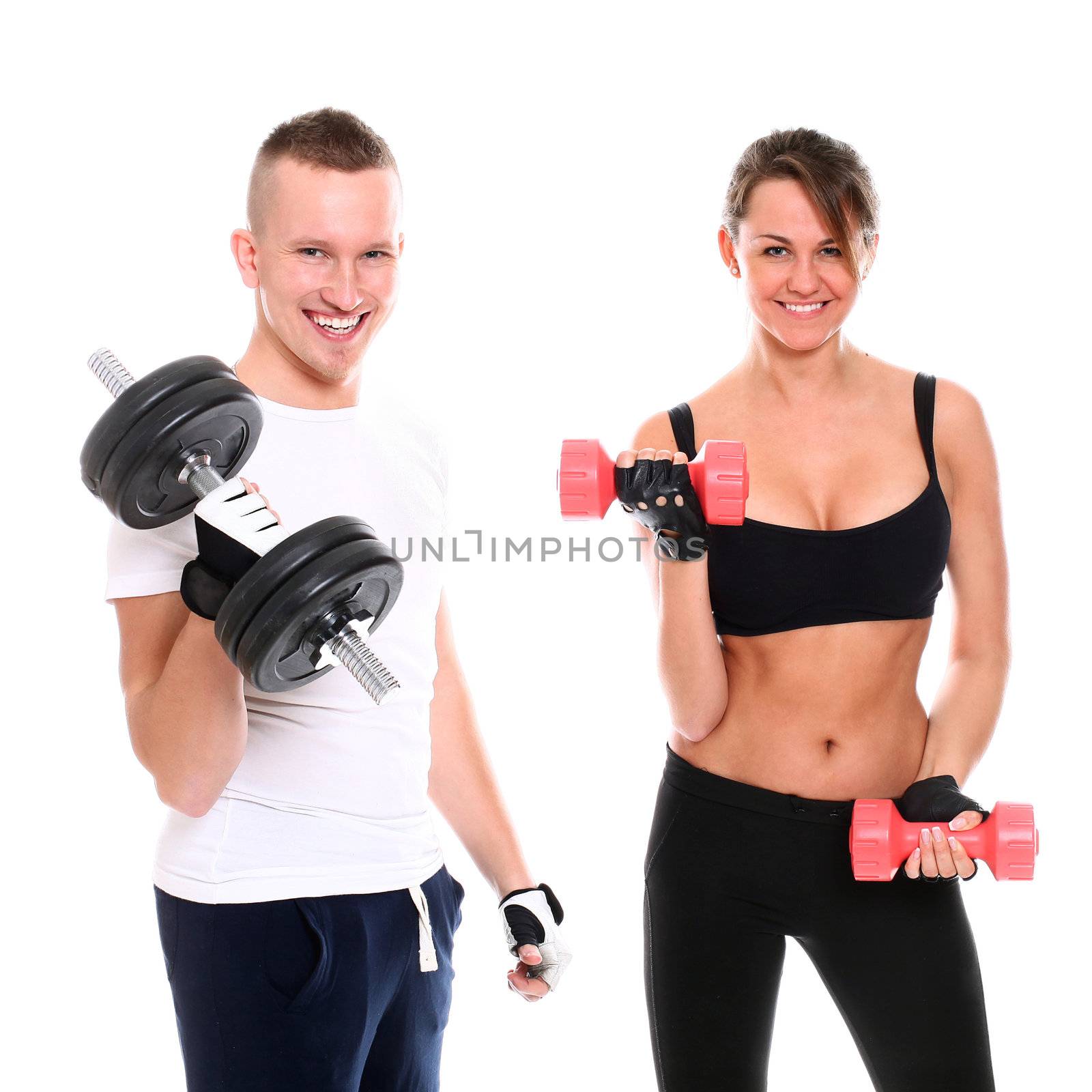 Young smiling couple lifting dumbbells in studio over a white background