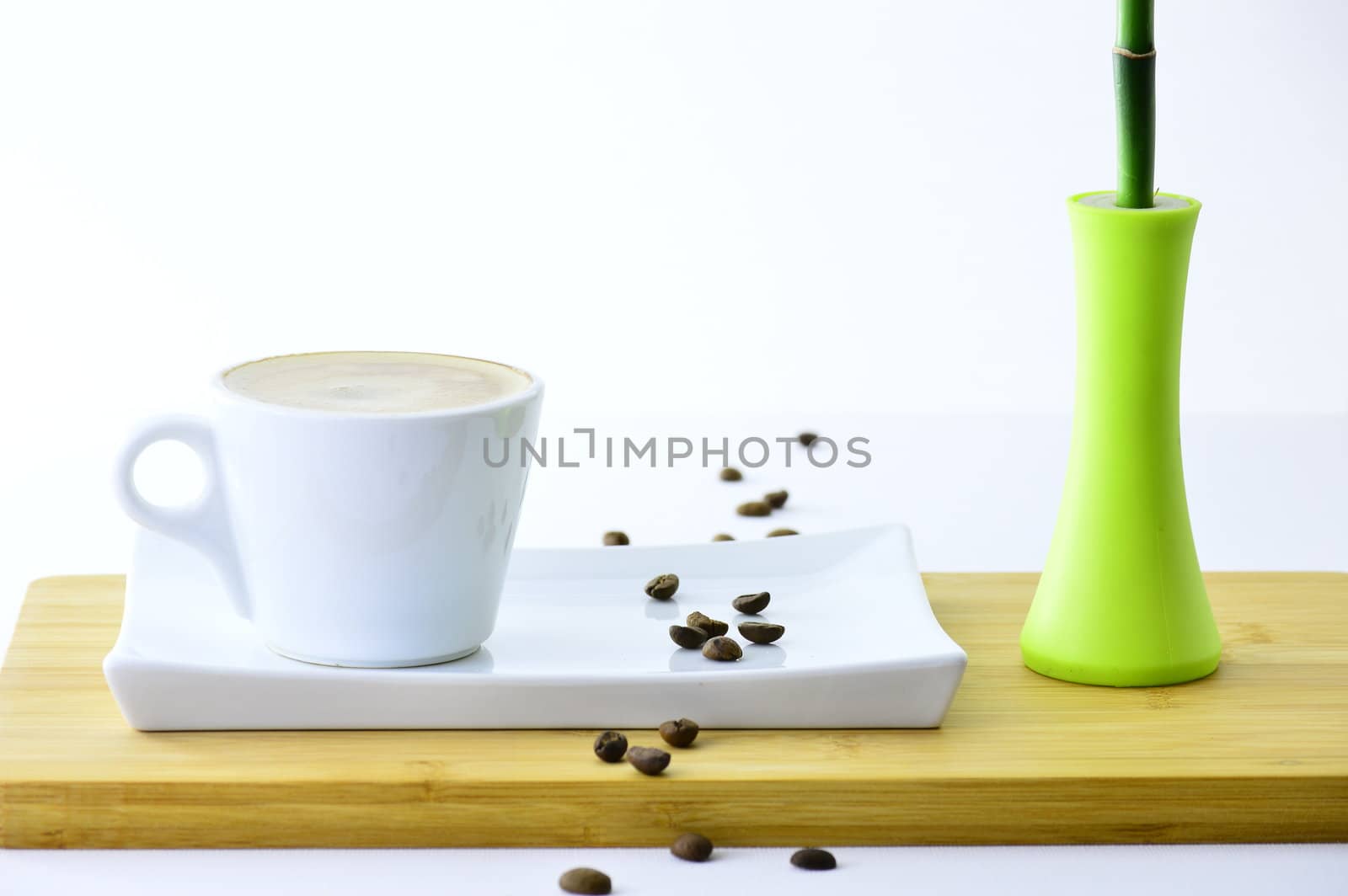coffee beans and cup of coffee on a plate next to a bamboo on white backgraund