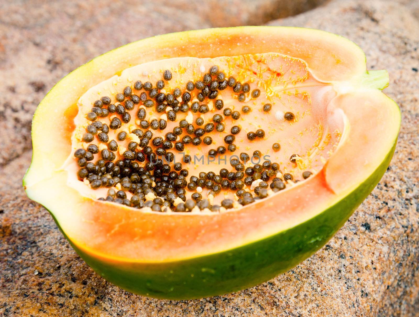 Ripe papaya cut in half on a stone