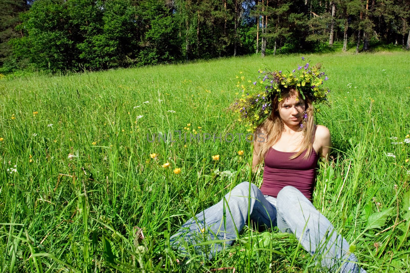 Young girl wearing flower wreath on summer forest meadow
