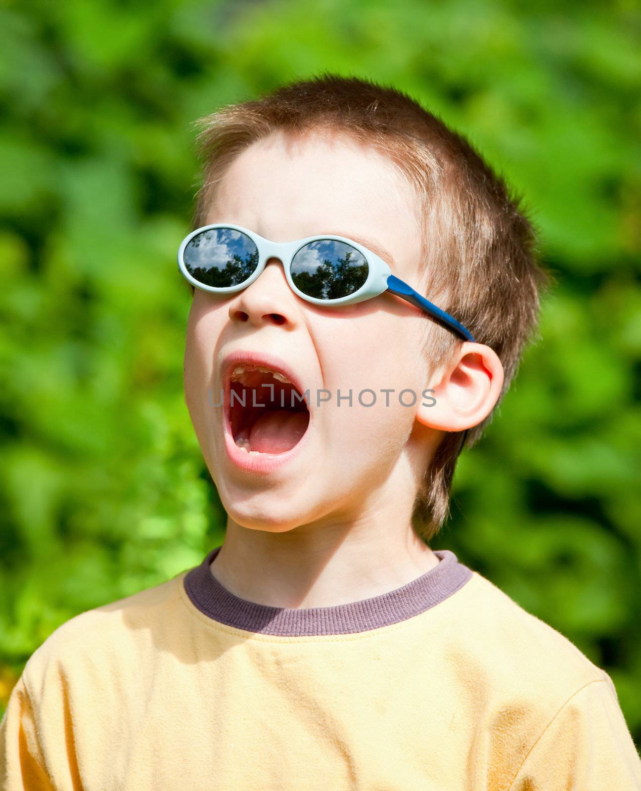 Young boy wearing sunglasses open-mouthed with surprise