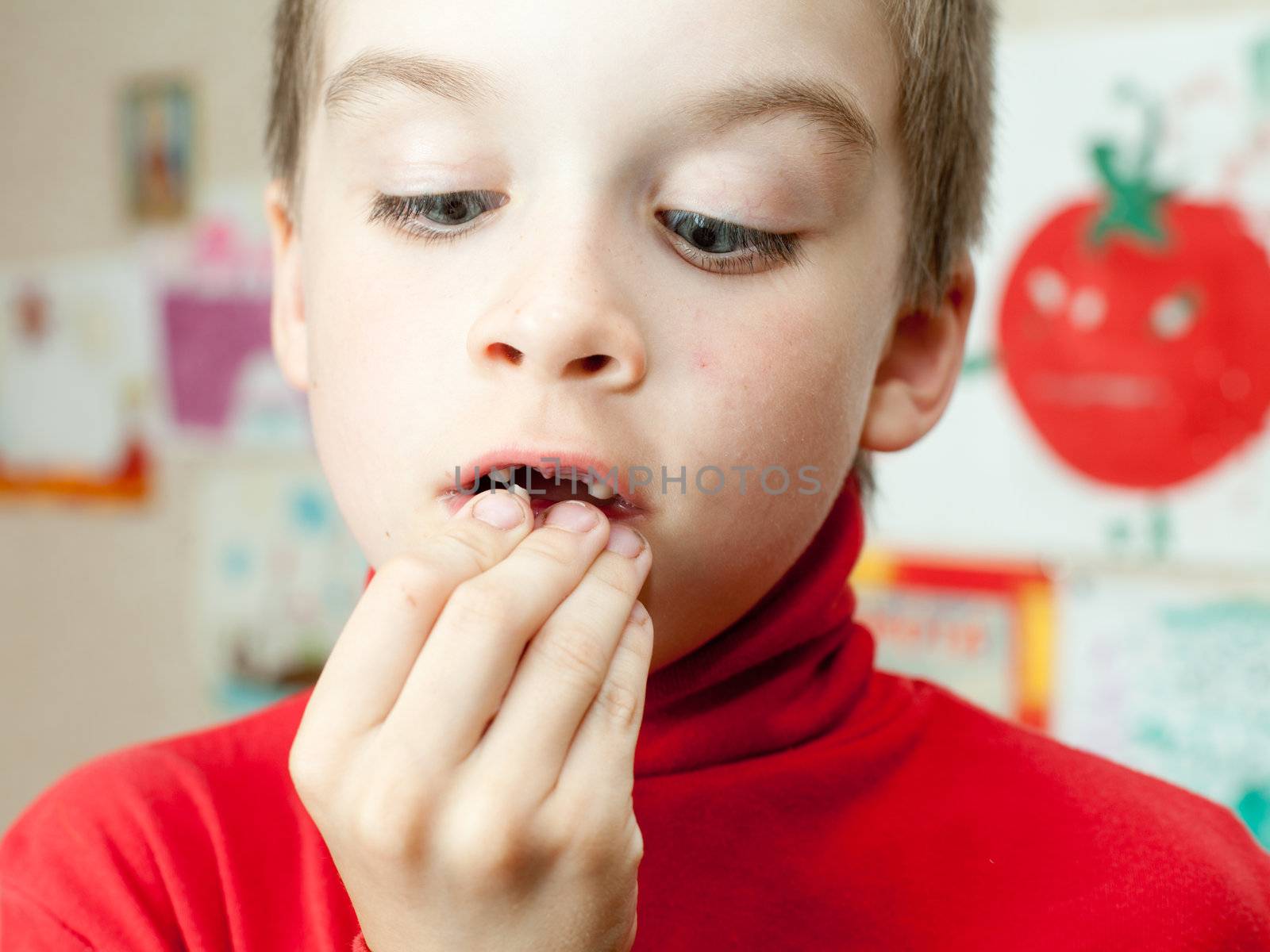Boy holding lost deciduous teeth against his drawing on the wall