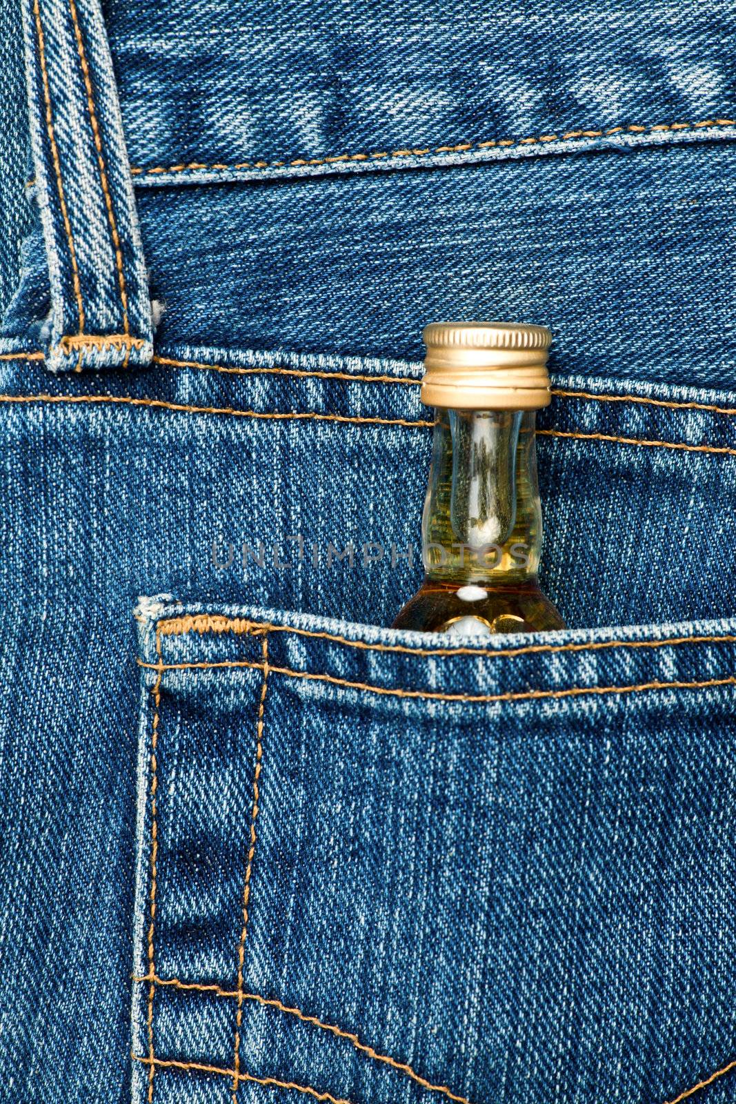 Blue jeans pocket with small bottle of alcohol