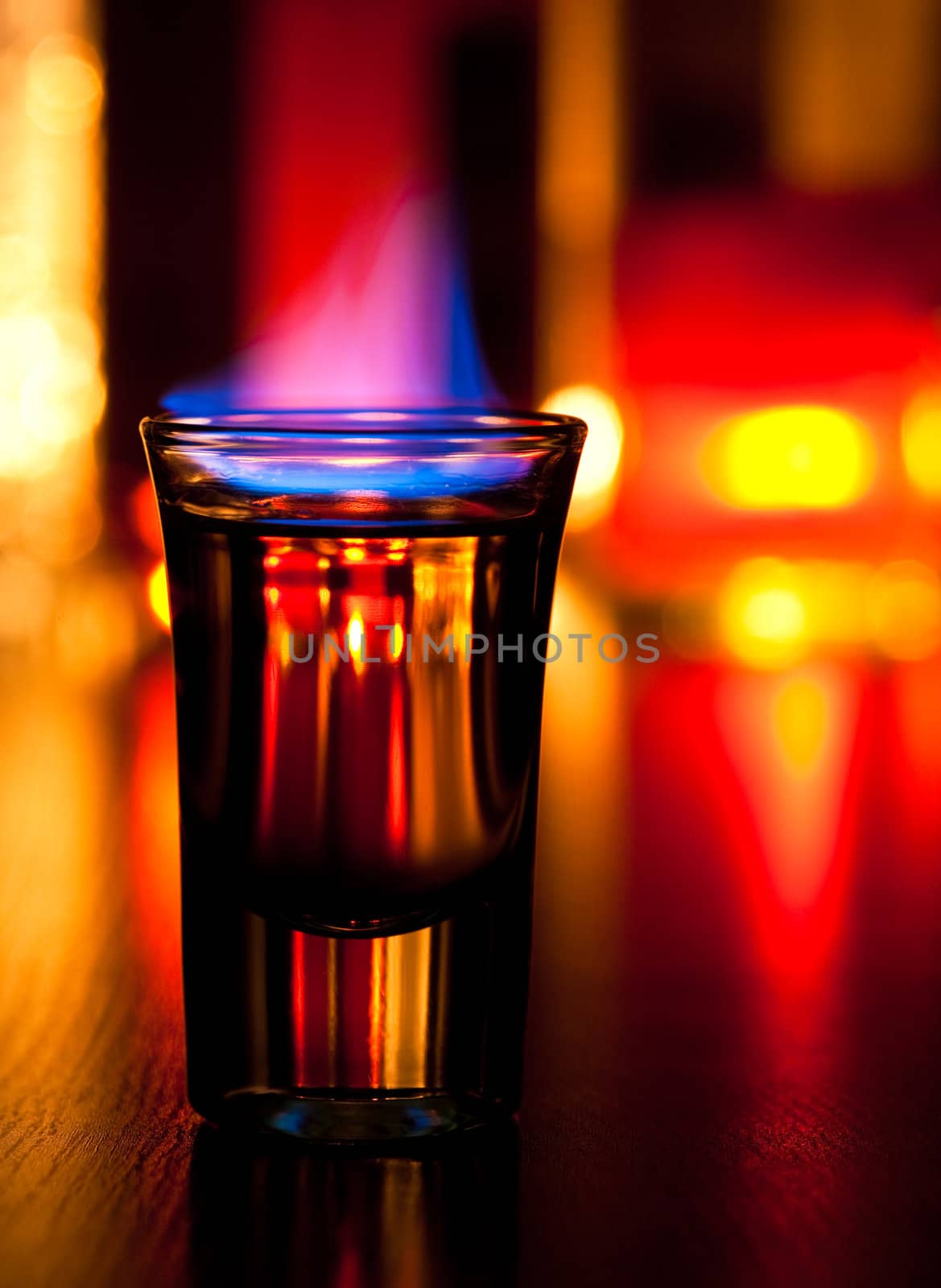 Burning cocktail in shot glass on a table, shallow focus