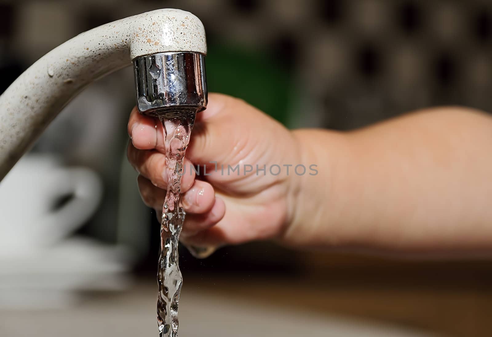 a child's hand is cooled down in the water from a tap