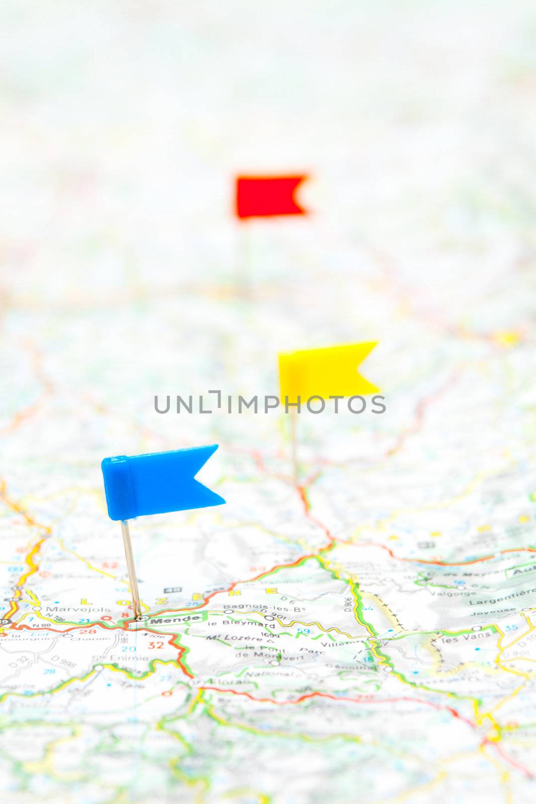 Three color flag pins on a map, shallow focus