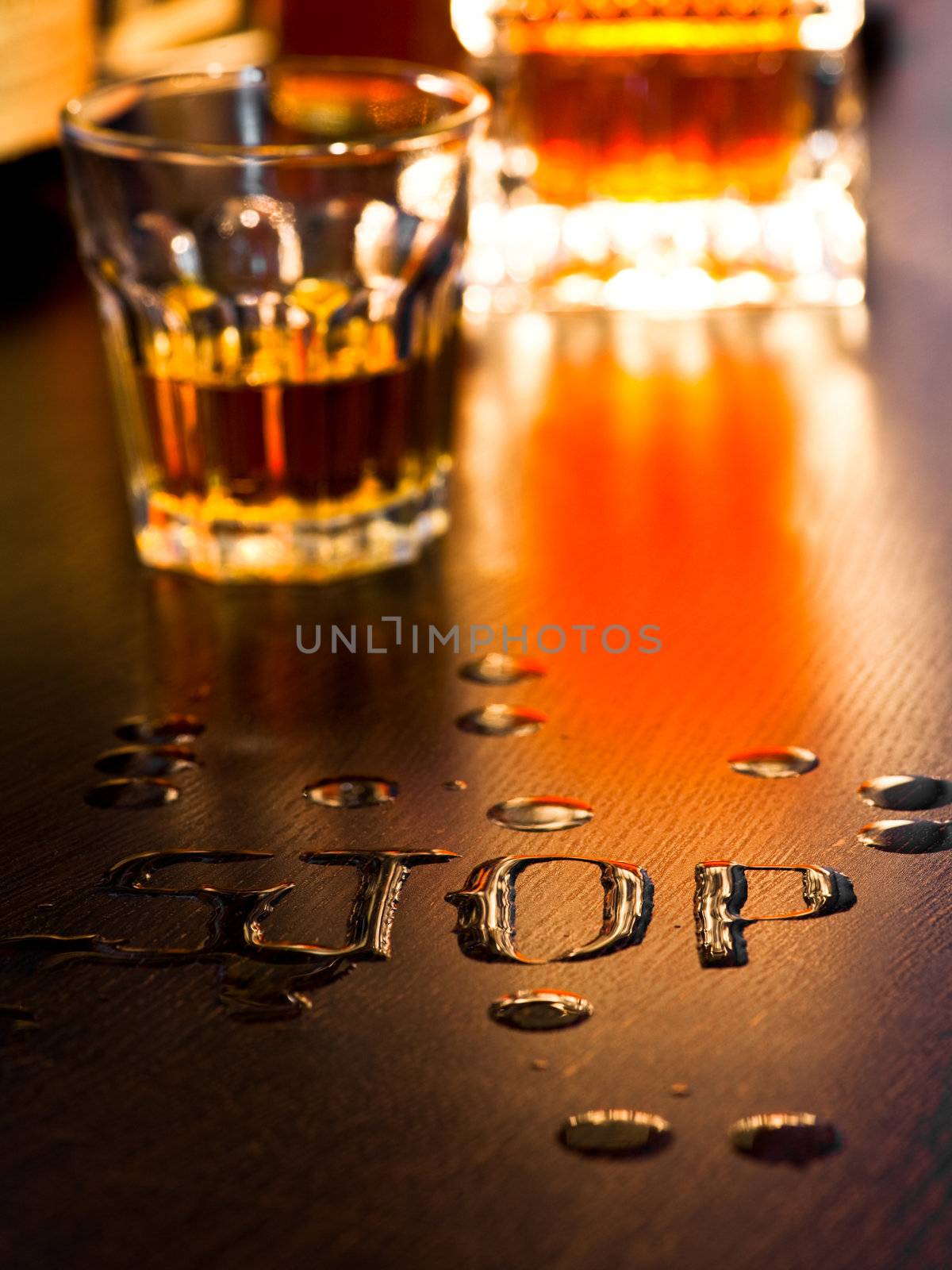 The word Stop written with spoiled whiskey on a table, shallow DOF