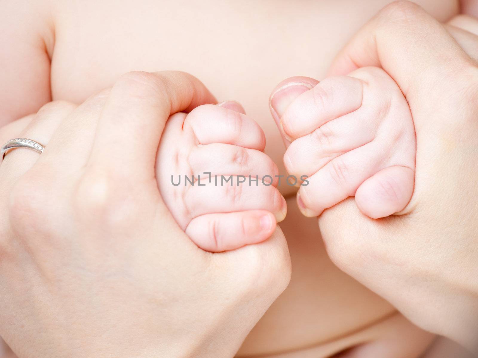 Infant holding mother's hands, shallow focus