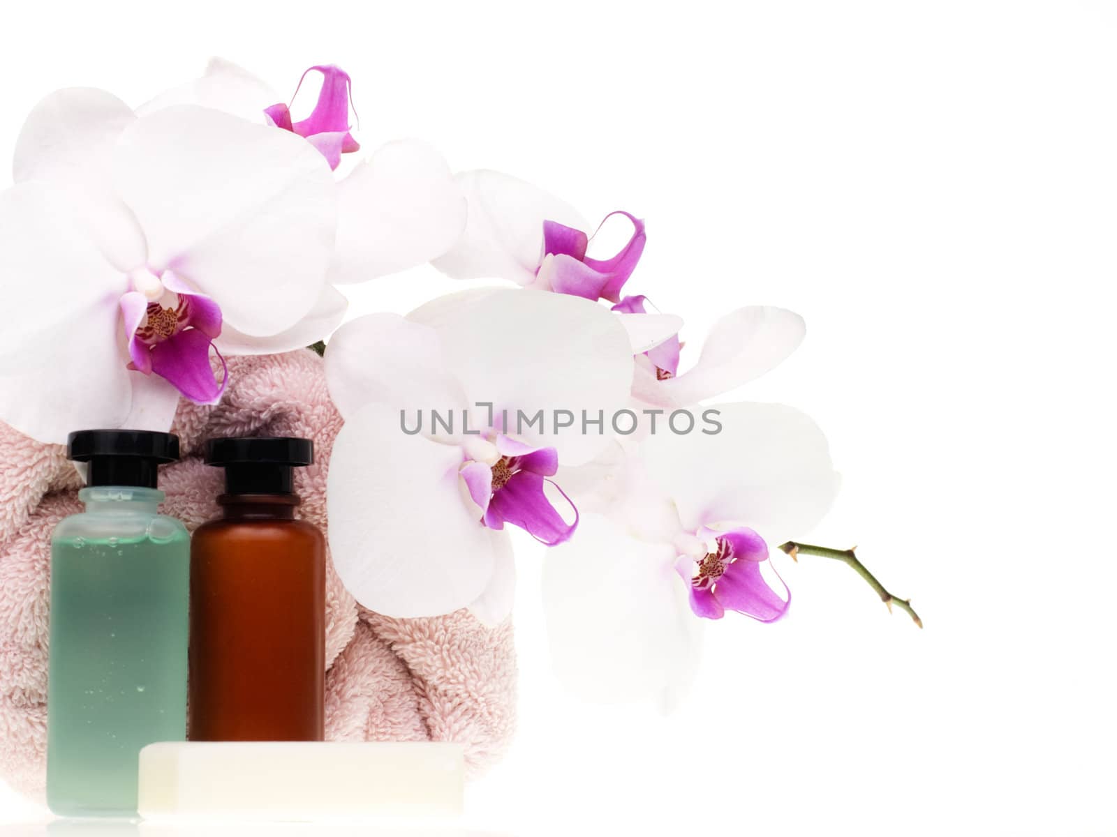 Spa set with white orchid, pink towel, bottles and soap on white background