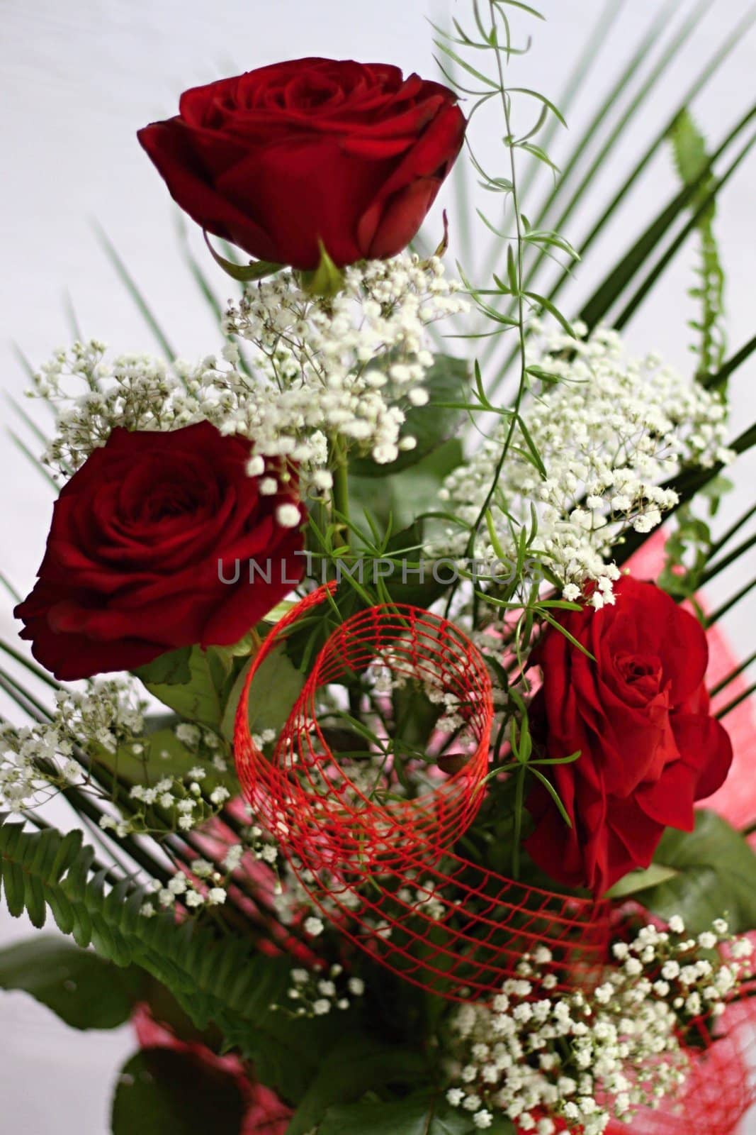 Three red roses and whitte flowers with green leafs