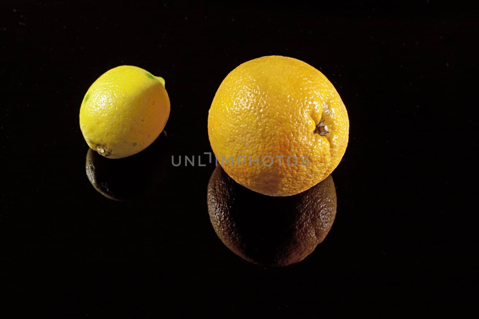 Orange and lemon on the black desk with shadows