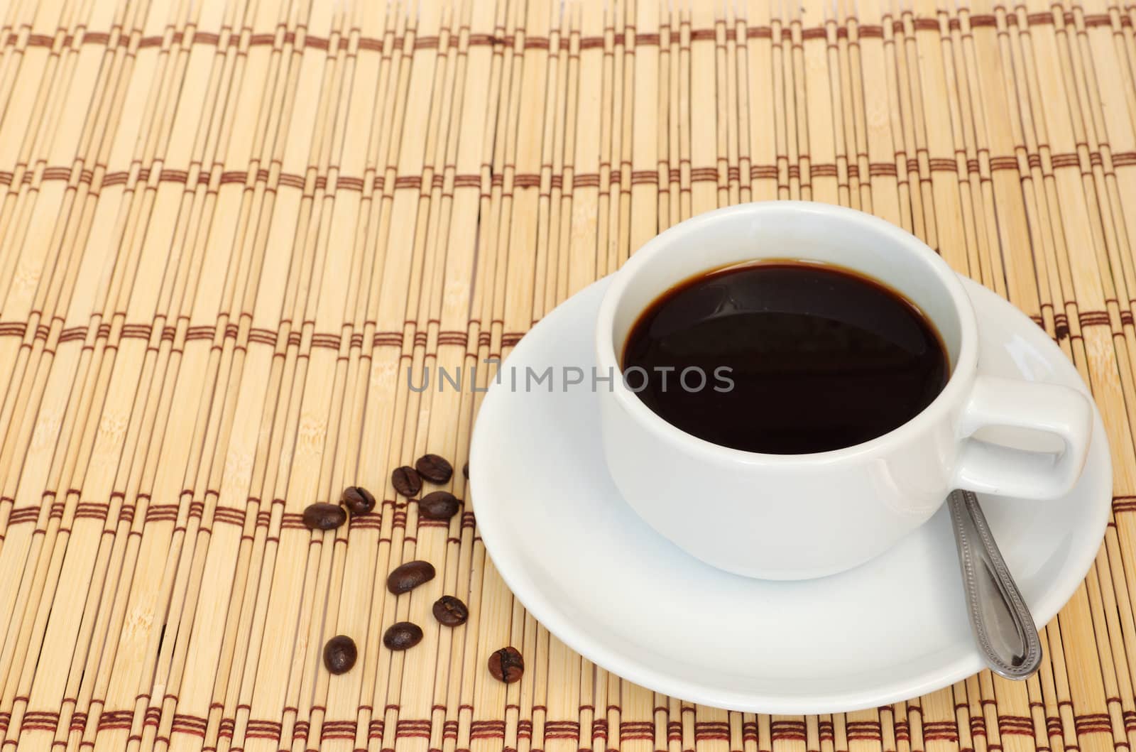 Cup of coffee with some coffee beans next to the cup, put on the table cloth made from wooden.