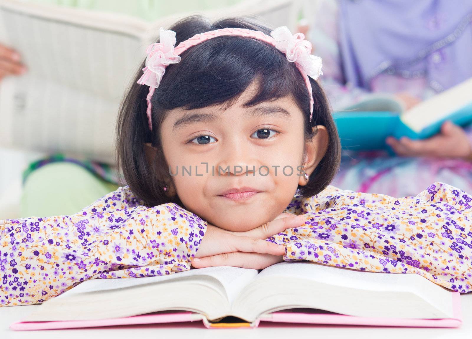 Muslim girl reading book at home. Southeast Asian family living lifestyle