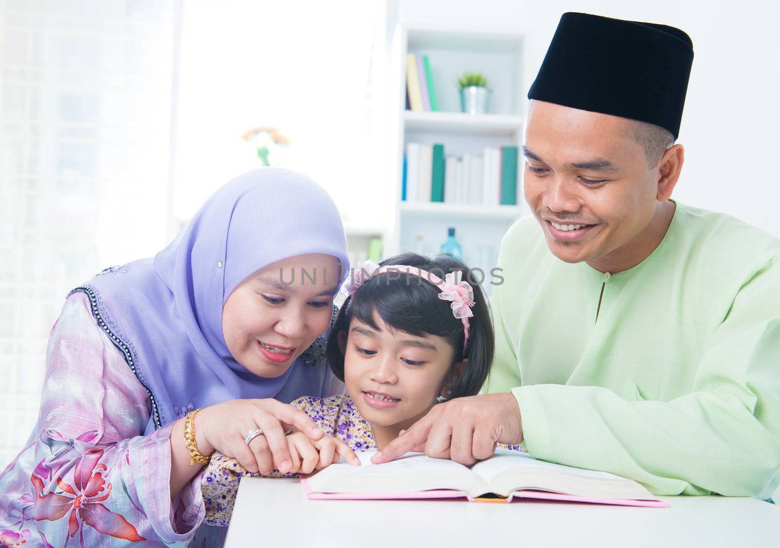 Muslim family reading book at home. Southeast Asian family living lifestyle