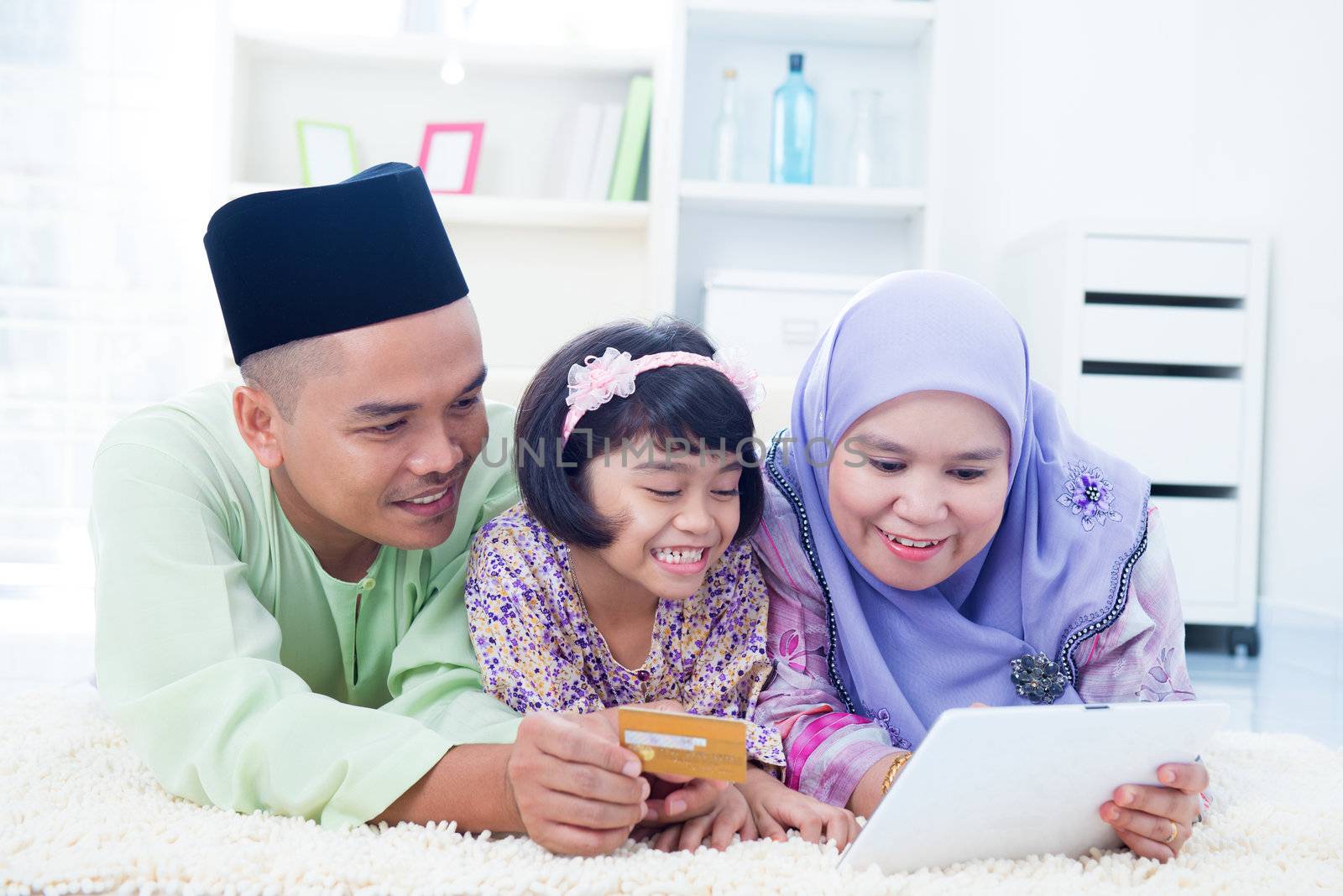 Southeast Asian family online shopping with credit card at home. Muslim family living lifestyle.
