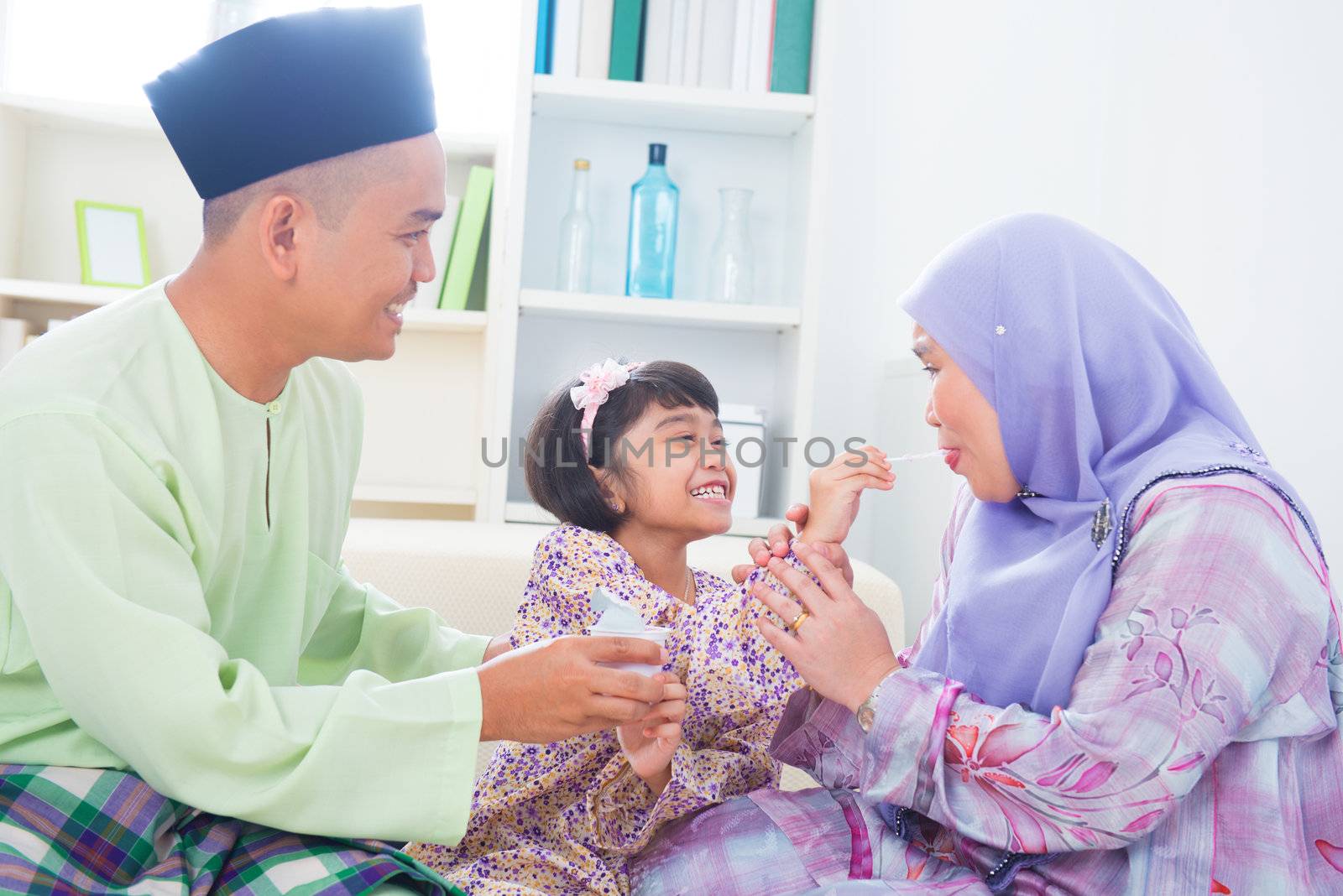 Southeast Asian child feeding mother yogurt. Malay Muslim family living lifestyle