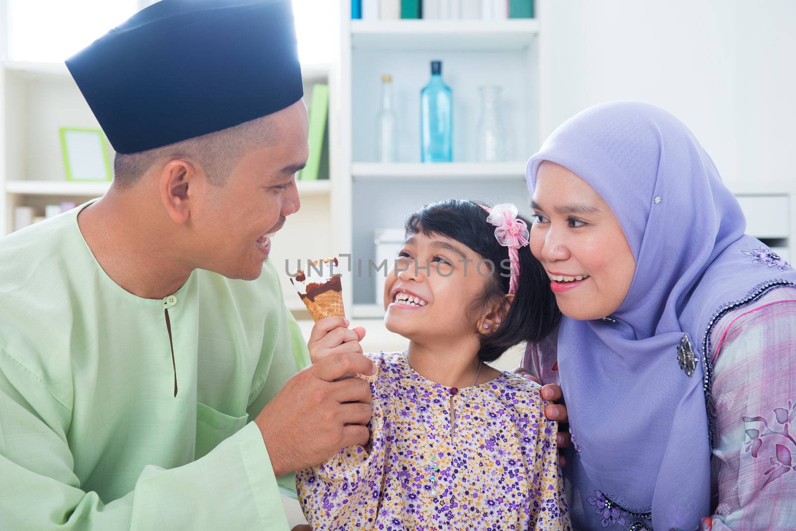 Southeast Asian girl feeding ice cream to father. Malay Muslim family lifestyle