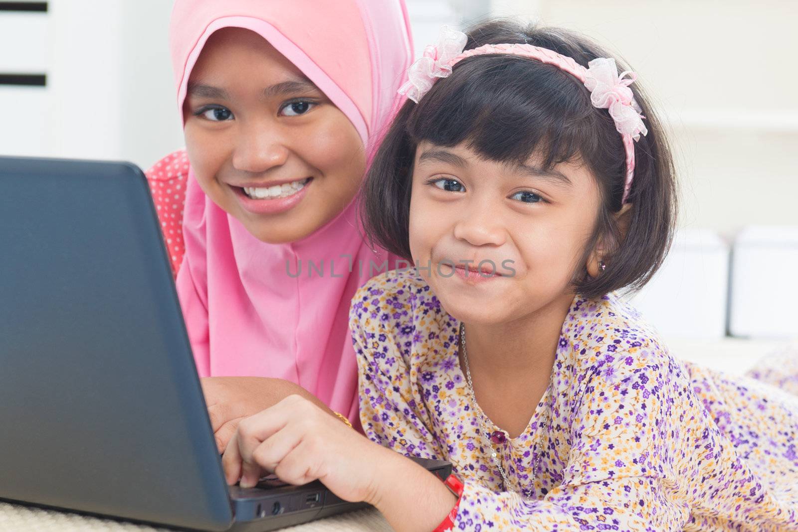 Southeast Asian children surfing internet at home. Malay Muslim girls