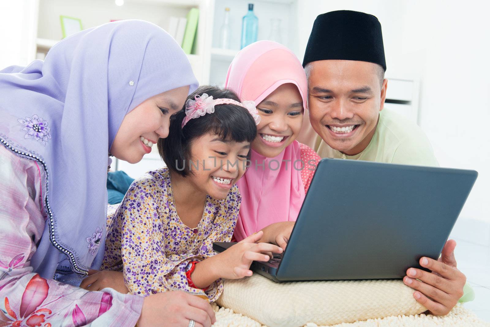 Southeast Asian family browsing internet at home. Lying on floor using computer laptop.