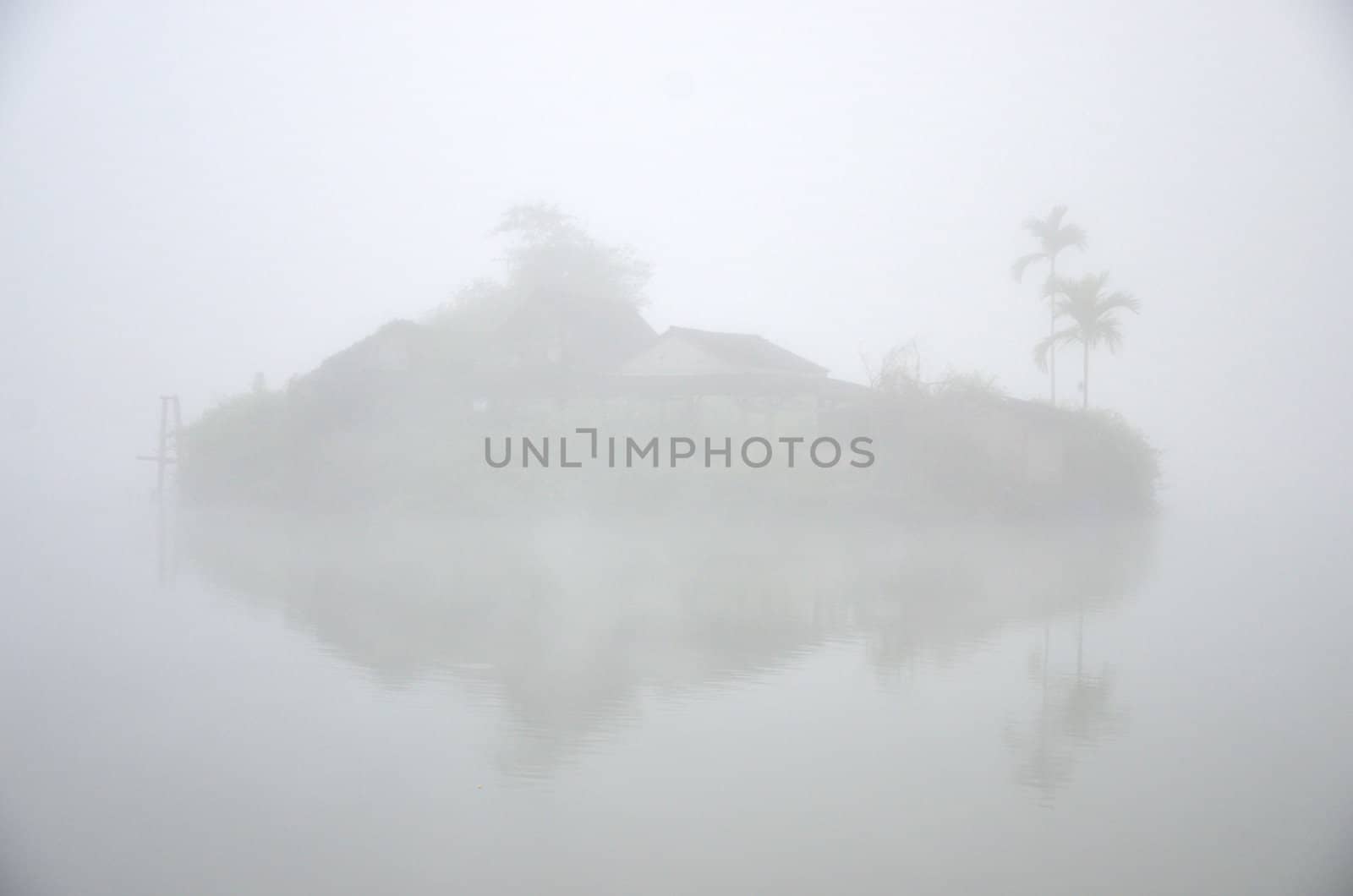 House on island in the lake with foggy background