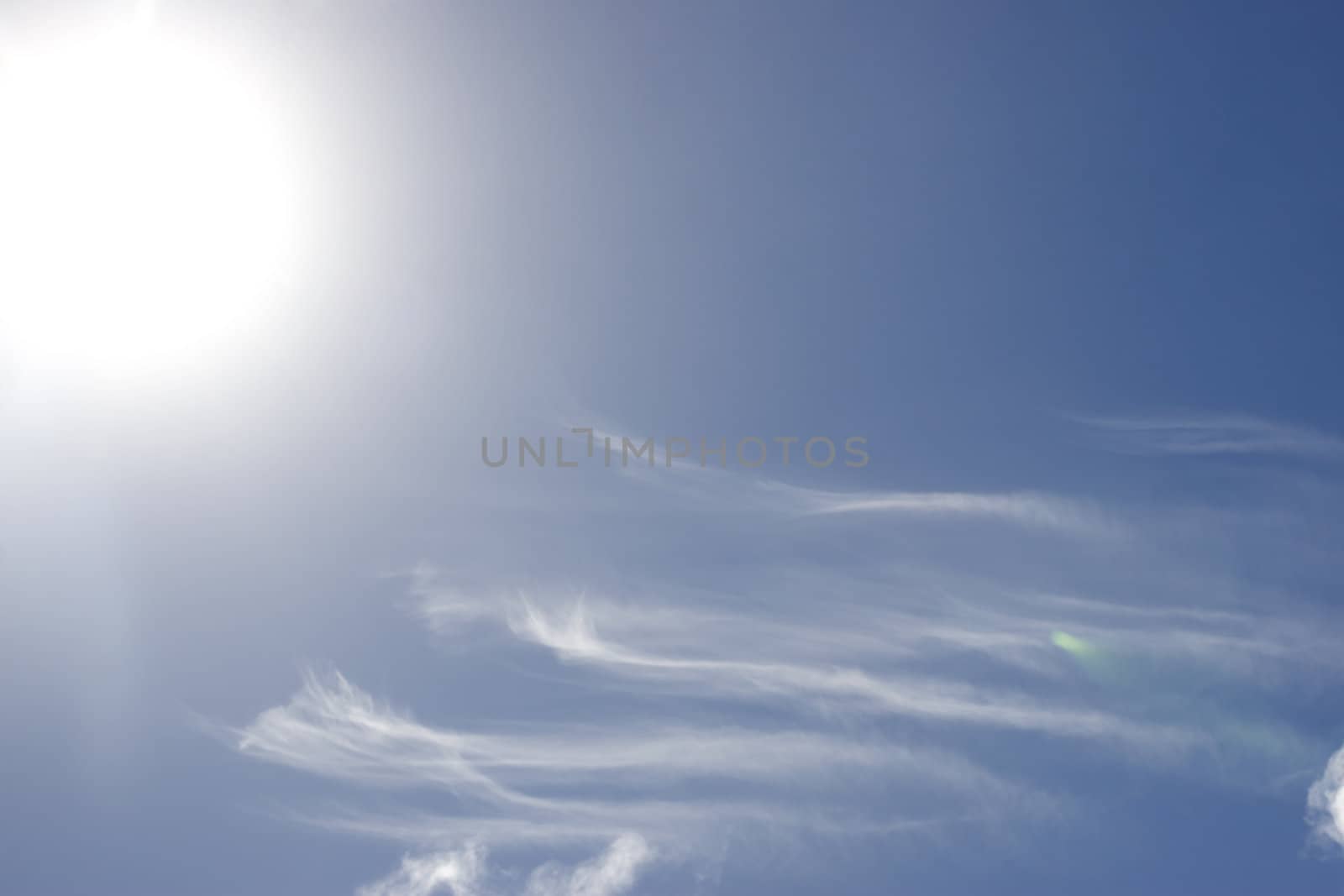 white fluffy clouds and trails against lovely blue sky with bright sun shine